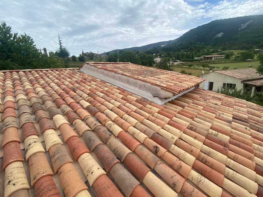 Toiture en tuiles canal surplombant une vallée de l'arrière-pays niçois