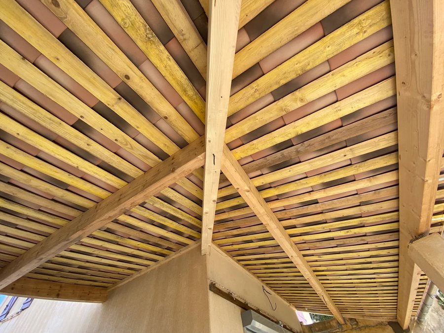 Charpente traditionnelle en bois avec chevrons et liteaunage vue depuis l'intérieur